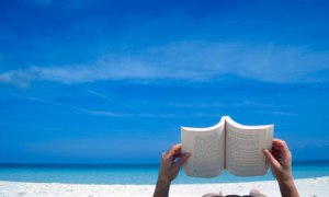 Person reading a book on the beach